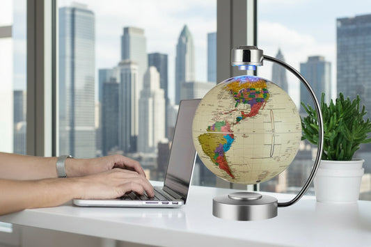Modern magnetic levitating globe displayed on a desk against a backdrop of a city skyline and large windows.