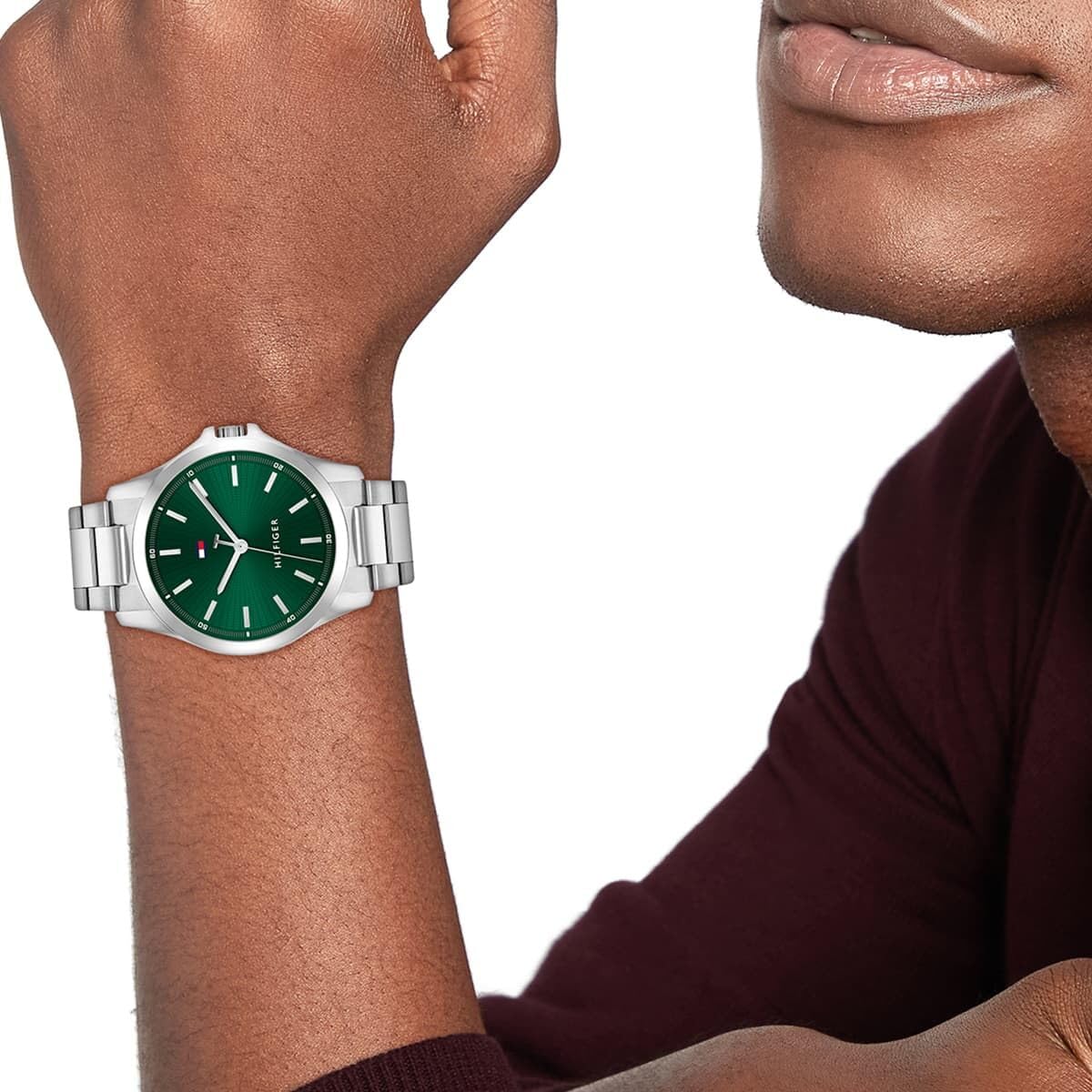 Close-up view of a Tommy Hilfiger men's watch with a green dial and silver-tone case, worn on a wrist.