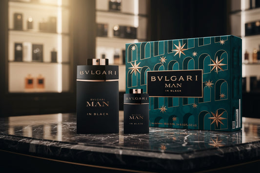Bvlgari Man In Black perfume bottles displayed on a reflective surface in front of a glowing city skyline at dusk.