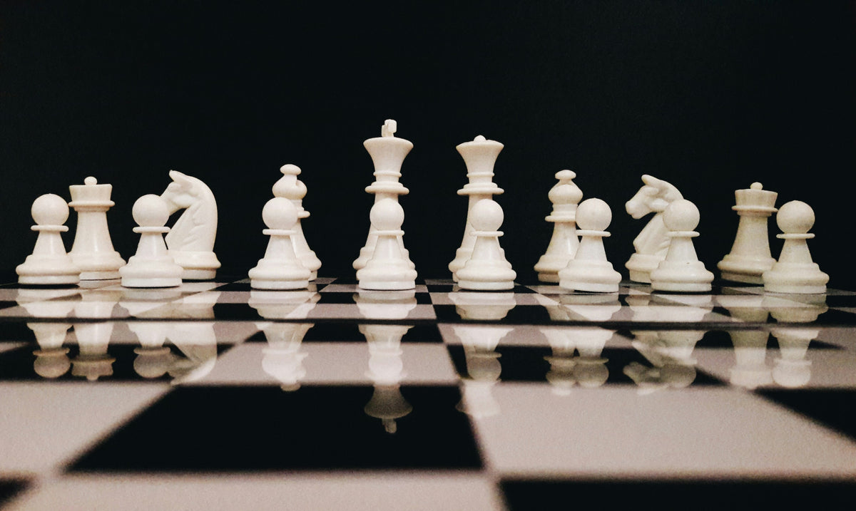 White chess pieces on a chessboard with a black background