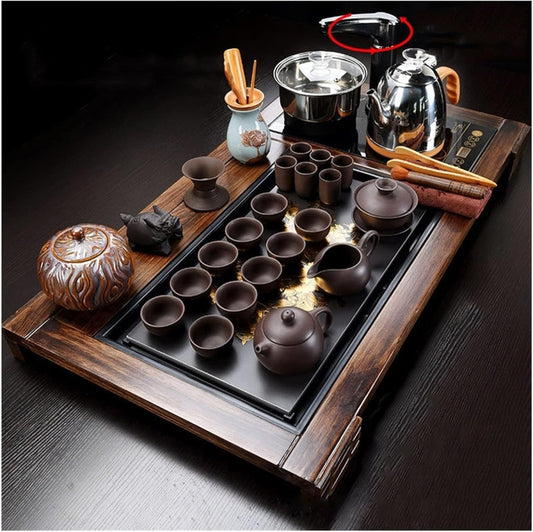 Detailed close-up shot of the dark wooden tea tray featuring the cast iron teapot and small matching cups, against a dark, moody background.