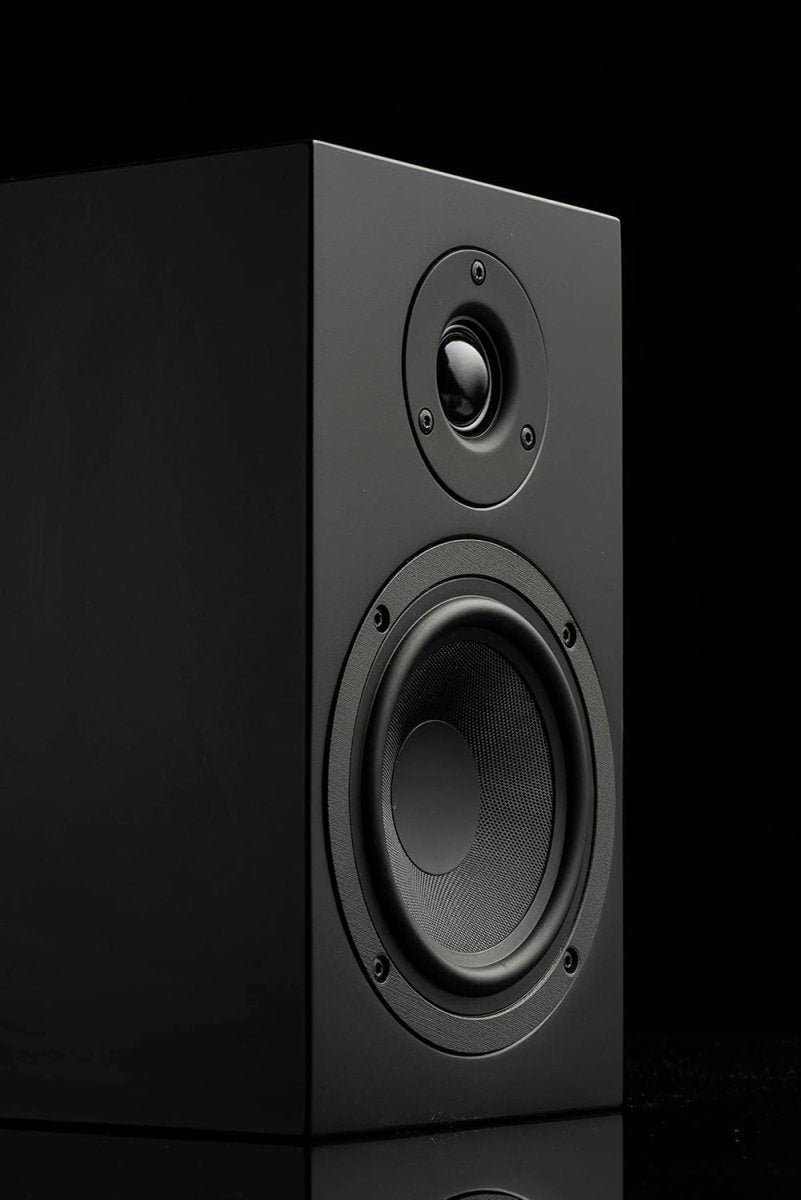 Studio product shot of a black bookshelf speaker against a dark background, highlighting its acoustic driver and tweeter.