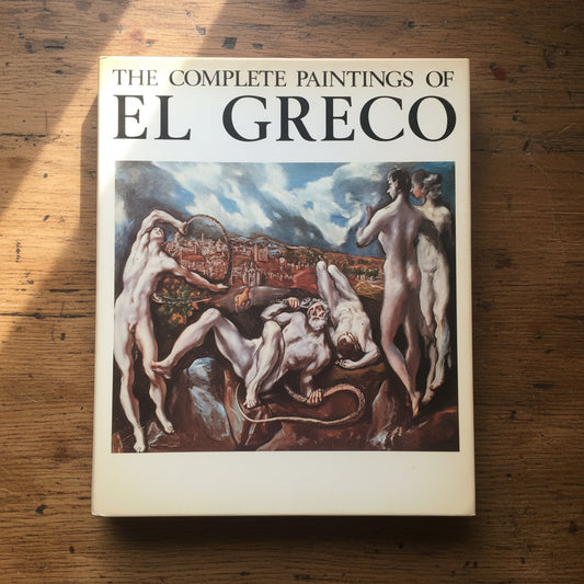 Art book titled 'The Complete Paintings of El Greco' with a classic painting featured on the cover, resting on a dark surface.