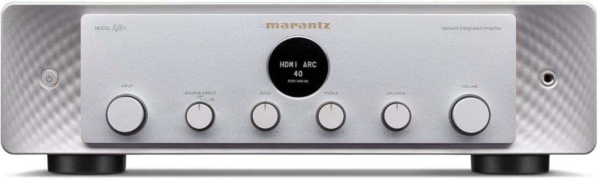 Front view of a premium silver audio receiver featuring a central display dial and multiple control knobs on a clean surface.