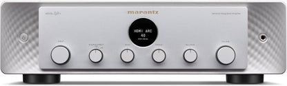 Front view of a premium silver audio receiver featuring a central display dial and multiple control knobs on a clean surface.