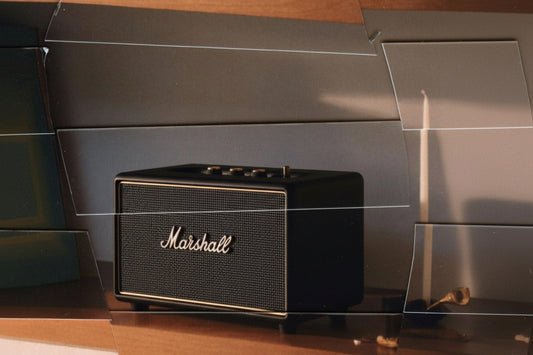 Marshall Stanmore III wireless Bluetooth speaker in black, placed neatly on a warm wooden shelf in a minimalist interior.