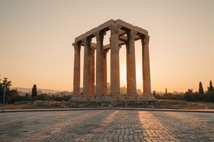 Classic ancient Greek temple silhouette standing proudly under a warm, golden sunset sky.